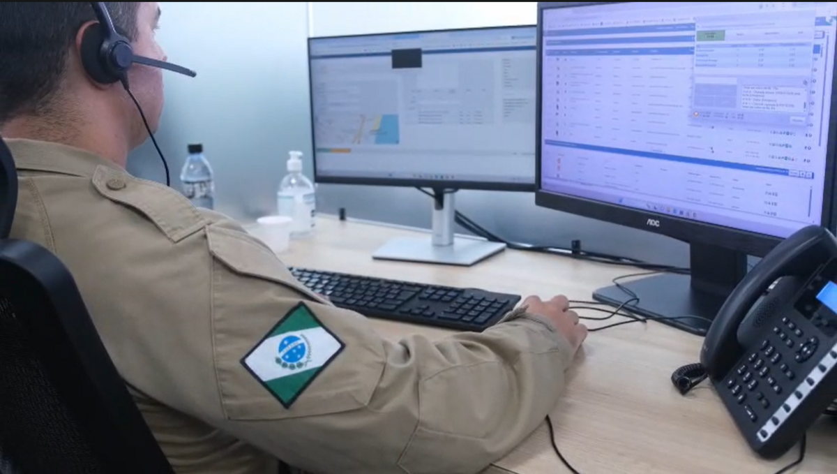 Policial militar opera computador em sala de videomonitoramento