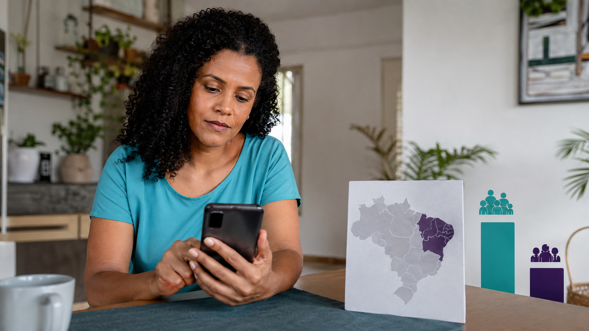Mulher sentada na mesa consulta empréstimo digital pelo celular ao lado de mapa do Brasil