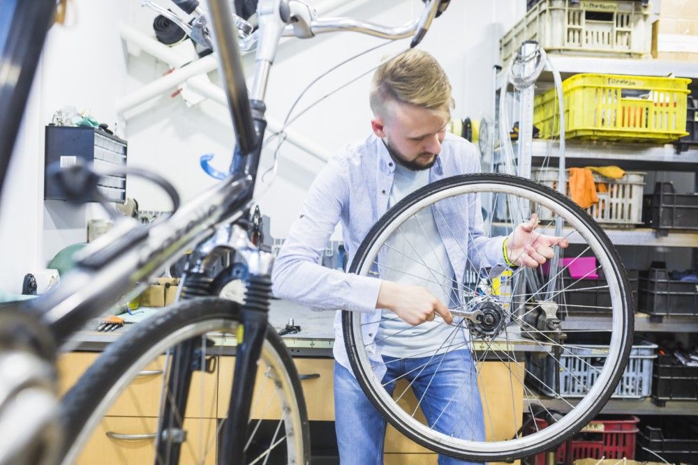 man-fixing-bicycle-tire-with-wrench-workshop