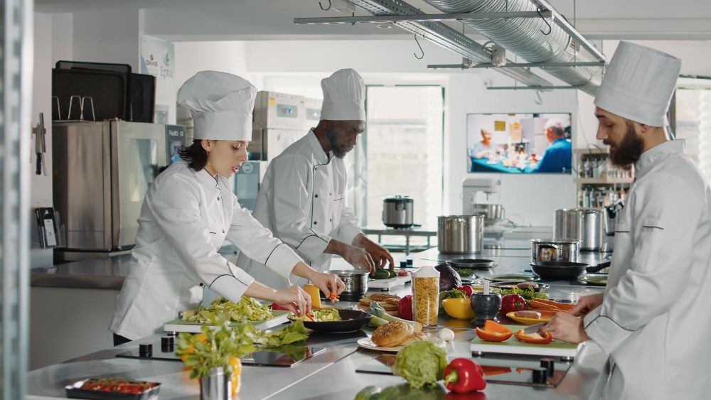 team-of-cooks-slicing-vegetables-on-cutting-board-for-meal-preparation-in-restaurant-kitchen-man-and-woman-cooking-gourmet-food-dish-with-organic-ingredients-working-on-culinary-recipe
