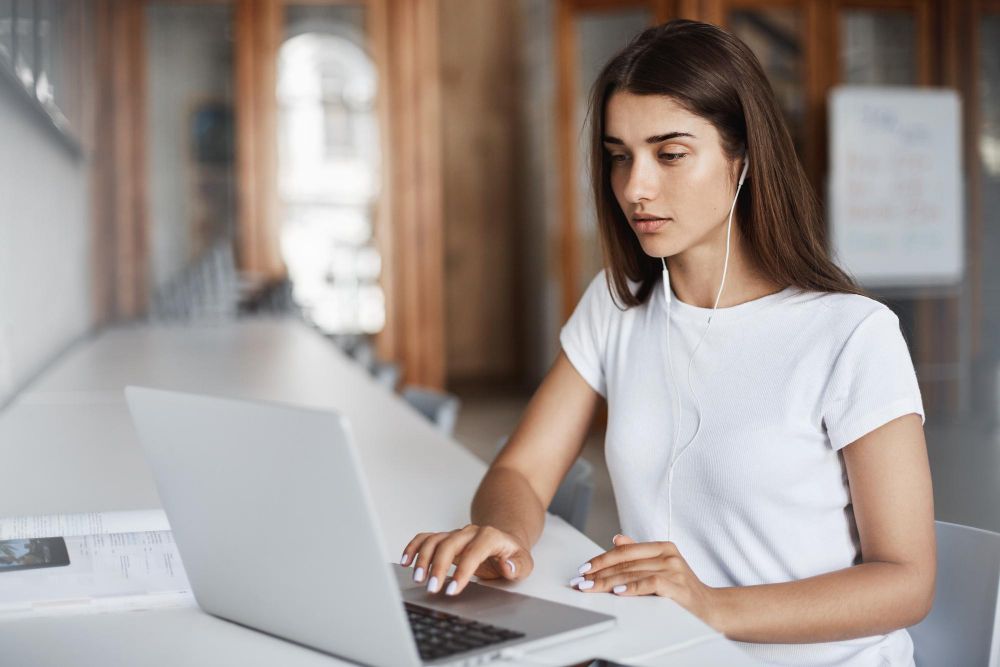 young-woman-using-a-notebook-computer-watching-streaming-movies-or-listening-to-online-music-in-university-campus