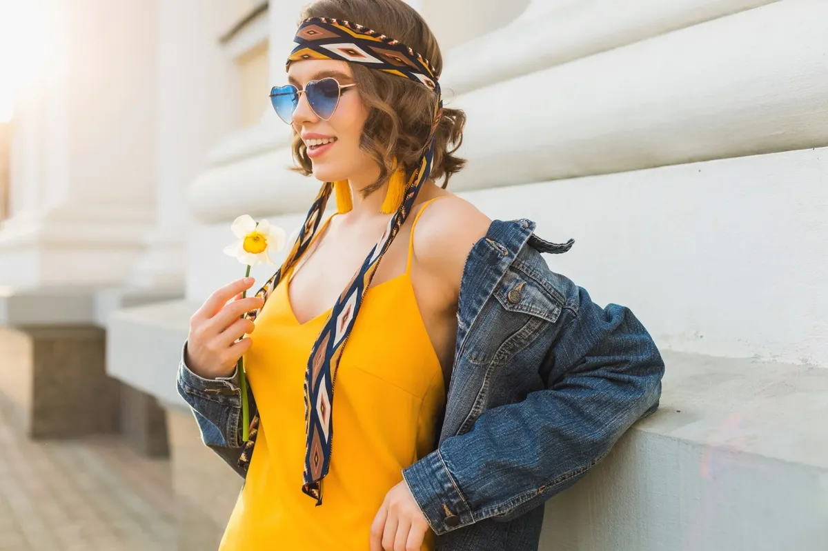 Mulher com vestido amarelo, jaqueta jeans e óculos de sol